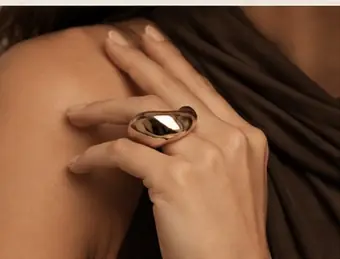 Detalhe de mão com anel dourado escultural