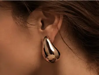 Detalhe de brinco dourado escultural